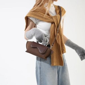 Detail of dark brown faux suede crossbody bag with silver metal handle on a model