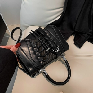 Detailed close-up of a black PU handbag with crisscross straps and metal buckles decoration
