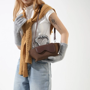 Detail of a deep brown suede handbag with a unique silver heart-shaped metal handle