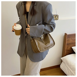 Close-up of minimalist olive green PU leather crossbody bag with elegant golden zipper