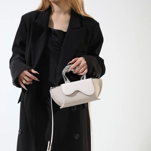 Chic ivory PU and suede handbag with unique silver metal handle shown on a model