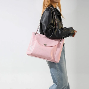 Détail d'un sac cabas en cuir froissé rose avec chaîne argentée et fermoir pivotant