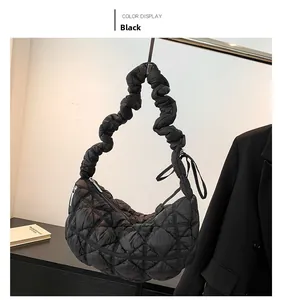 Detail of black quilted puffer bag showing glossy fabric and scrunchie handle texture