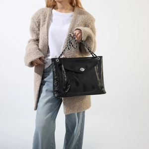 Détail du sac cabas en cuir verni noir avec bandoulière chaîne et fermoir tournant