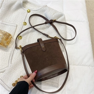 Detail of vintage brown suede bucket bag with leather trim and gold-tone metal hardware