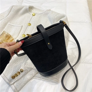 Detail of a chic black bucket bag featuring suede and leather textures with gold hardware