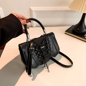 Detail view of gothic style black PU leather handbag with crisscross lacing and silver hardware
