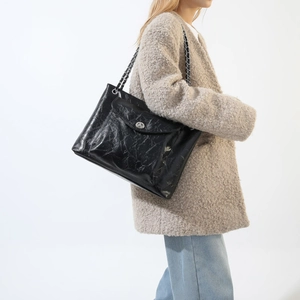 Détail du sac en similicuir plissé noir avec fermoir rotatif argenté et chaîne