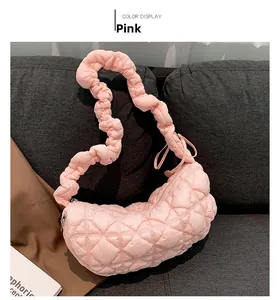 Detailed close-up of pink quilted cloud bag with elastic ruched strap on a gray sofa