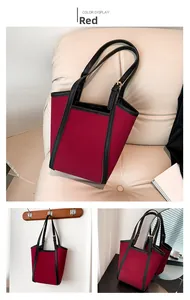 Detail of red canvas tote bag with black leather straps on a beige sofa