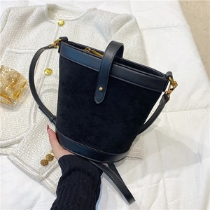 Top view of a black bucket bag with gold zipper and hardware on white textured background