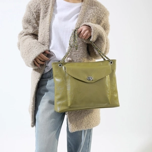 Détail d'un sac cabas vert en similicuir avec chaîne argentée et fermoir pivotant