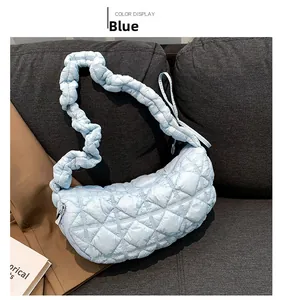 Close-up of a light blue quilted shoulder bag with a unique ruched strap and silver zipper