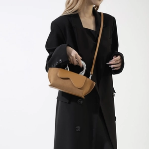 Detail of a brown suede and PU leather handbag with a silver wave metal handle