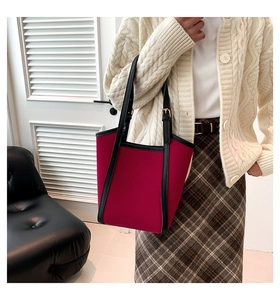 Detail of burgundy tote bag with adjustable golden hardware and elegant black edge finish