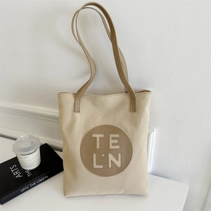 Detail view of canvas tote bag featuring premium leather handles and TELN logo patch