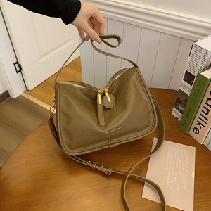 Close-up of olive green crossbody bag showing premium PU leather texture and dual gold zippers