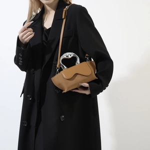 Detail view of brown suede shoulder bag featuring a unique silver metallic hollow handle