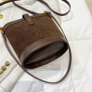 Detail of dark brown bucket bag featuring textured suede and smooth leather stitching