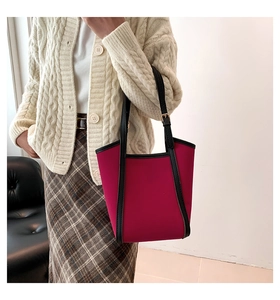 Detail of fuchsia tote bag on model arm showing black straps and premium fabric texture