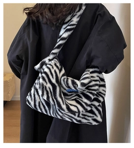 Detail view of a large zebra print plush tote bag worn by a model for a stylish winter look