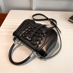 Close-up of black PU handbag with unique cross-strap design and silver metal buckles