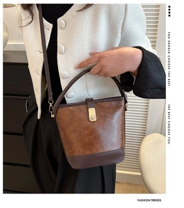 Detailansicht einer braunen Vintage-Eimertasche mit goldener Schließe und Leder
