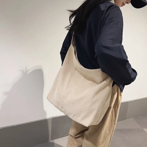 Dettaglio di una grande borsa a tracolla in velluto a coste color panna con spallina