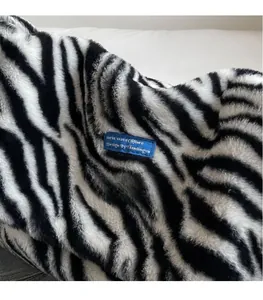 Detailed macro view of zebra pattern plush fabric and signature blue woven label on bag