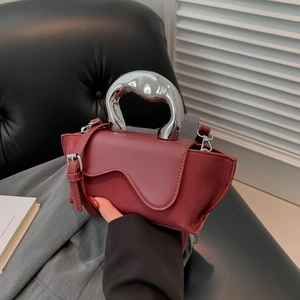Detail of burgundy PU and suede handbag featuring a unique silver metallic handle
