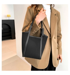 Detail of minimalist black tote bag featuring adjustable golden buckle and premium texture