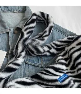 Detailed close-up of plush faux fur shoulder strap with zebra pattern on denim jacket