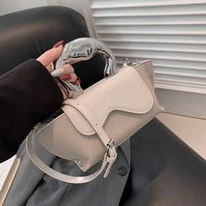 Close-up of stylish handbag with unique liquid silver metal handle and cream leather