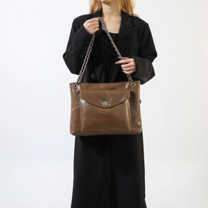 Sac bandoulière en cuir verni marron avec chaîne argentée et fermoir pivotant en métal