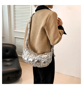 Close-up of quilted metallic silver crescent bag with padded strap on a model