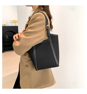 Close-up of black PU tote with gold hardware buckles and leather trim details