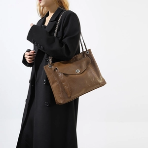 Détail du sac bandoulière marron en cuir glacé avec fermoir rotatif argenté et chaîne