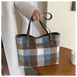 Detail shot of the plush plaid tote bag featuring leather handles and metal rivet hardware