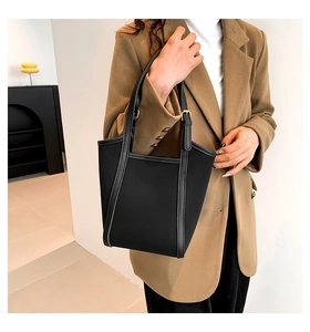 Minimalist black tote bag shown with model in a stylish workplace outfit