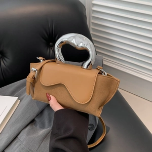 Close-up of the stylish suede and leather handbag featuring a unique silver curved handle