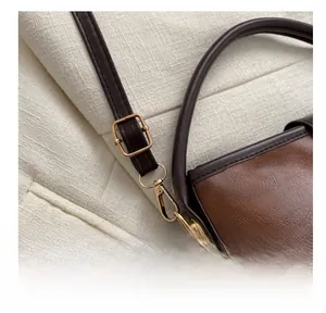 Detail der dunkelbraunen Lederhandtasche mit goldener Hardware und verstellbarem Riemen
