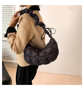 Detail of a black quilted cloud bag showing ruffled shoulder strap and crescent moon shape