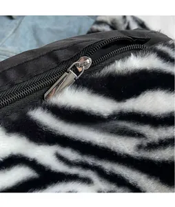 Detail of silver metallic zipper on plush zebra print bag with premium faux fur texture