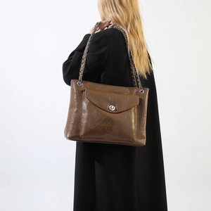Détail du sac en similicuir caramel avec bandoulière en chaîne et fermoir pivotant