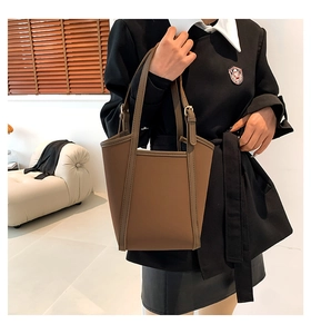 Close-up of matte brown leather tote bag showing stitching details and buckle