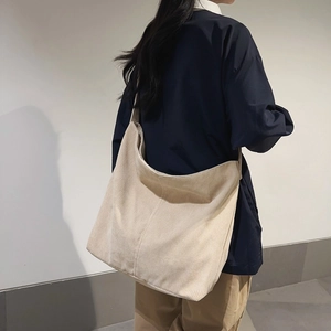 Dettaglio della borsa tote minimalista in velluto a coste crema indossata dalla modella