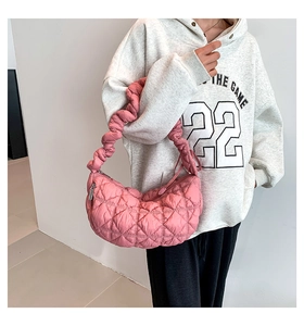 Detail view of pink quilted half-moon shoulder bag with ruched handle and diamond pattern