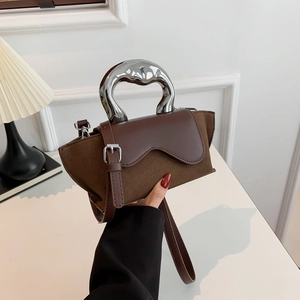 Detail of a brown suede handbag featuring a unique silver metallic geometric handle