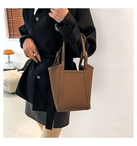 Detail shot of a brown PU leather tote bag showing stitching and metal buckle details