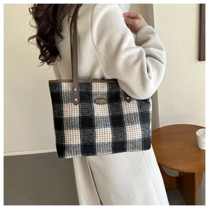 Detail of winter plaid tote bag featuring checkered wool fabric and leather handles